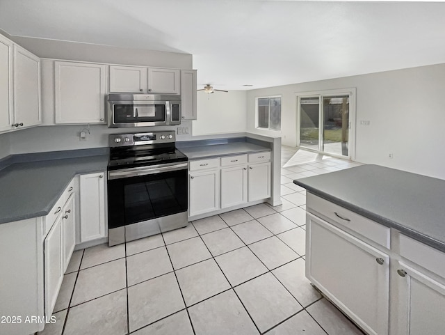 kitchen featuring stainless steel appliances, white cabinetry, light tile patterned floors, and ceiling fan