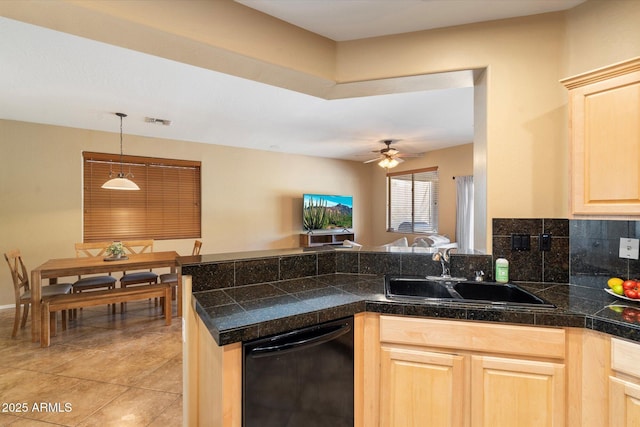 kitchen featuring tile countertops, a peninsula, a sink, black dishwasher, and light brown cabinetry