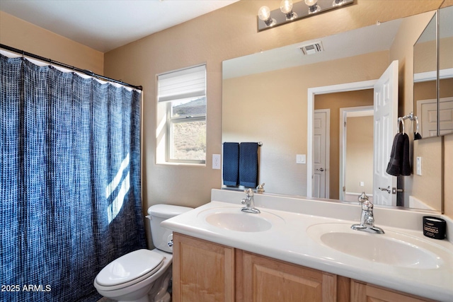 bathroom featuring toilet, double vanity, a sink, and visible vents