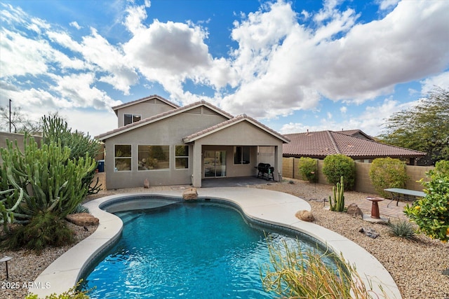 rear view of house with a fenced in pool, a patio, a tile roof, a fenced backyard, and stucco siding