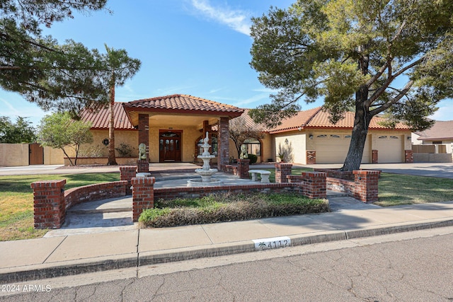 mediterranean / spanish-style house featuring a tiled roof, an attached garage, driveway, and stucco siding