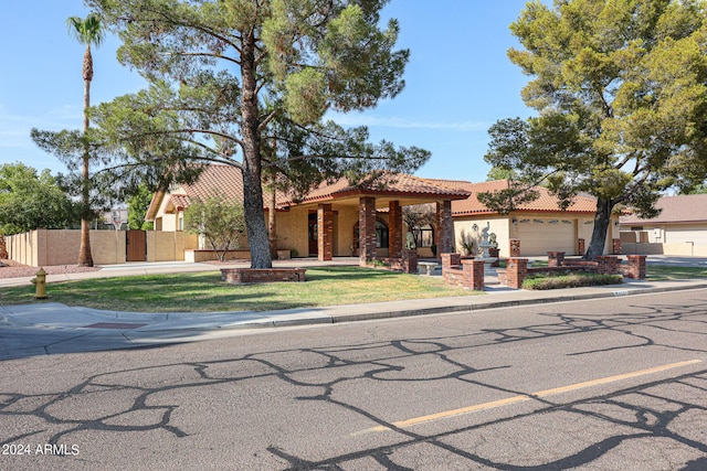 view of front of property with stucco siding, a tile roof, a front lawn, and fence