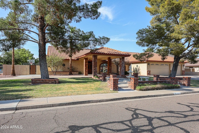 mediterranean / spanish-style house with a garage, stucco siding, a tile roof, and a front lawn