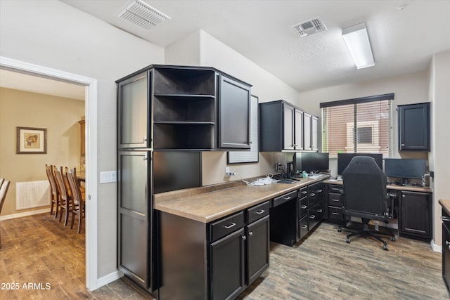 office featuring baseboards, visible vents, and wood finished floors