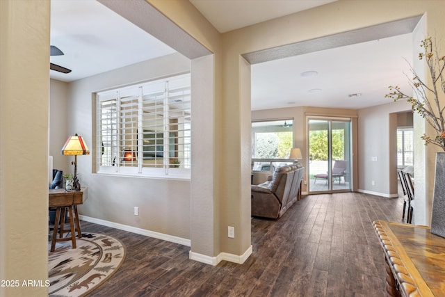 interior space featuring ceiling fan, a fireplace, baseboards, and wood finished floors