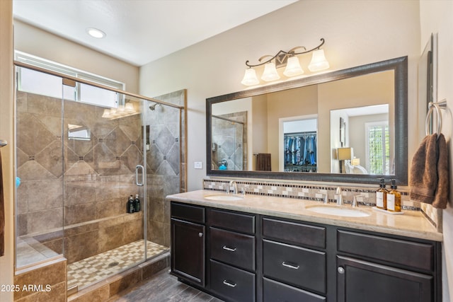 bathroom featuring a stall shower, a sink, decorative backsplash, and double vanity