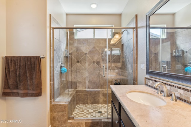 full bath featuring tasteful backsplash, a stall shower, a healthy amount of sunlight, and vanity