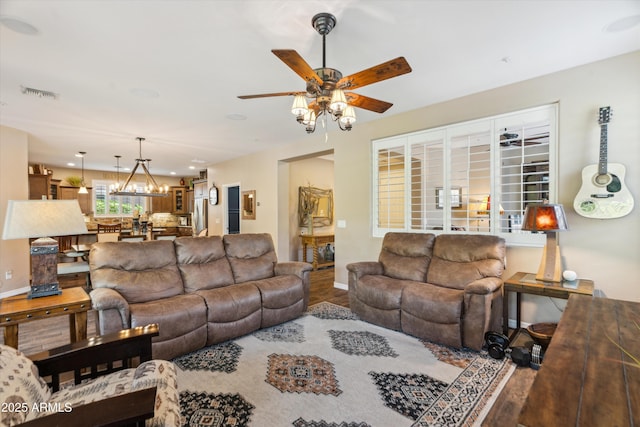 living area with baseboards, visible vents, wood finished floors, and ceiling fan with notable chandelier