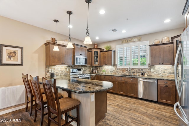 kitchen featuring a peninsula, appliances with stainless steel finishes, a sink, and visible vents