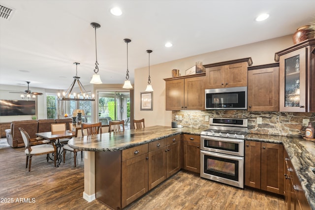 kitchen with visible vents, decorative backsplash, appliances with stainless steel finishes, glass insert cabinets, and a peninsula