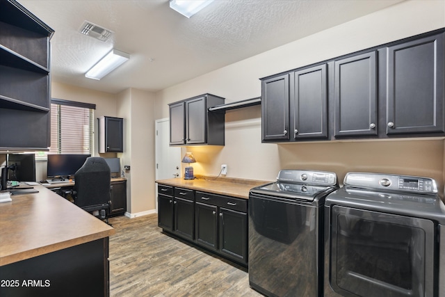 laundry area with cabinet space, visible vents, light wood-style flooring, a textured ceiling, and washing machine and dryer