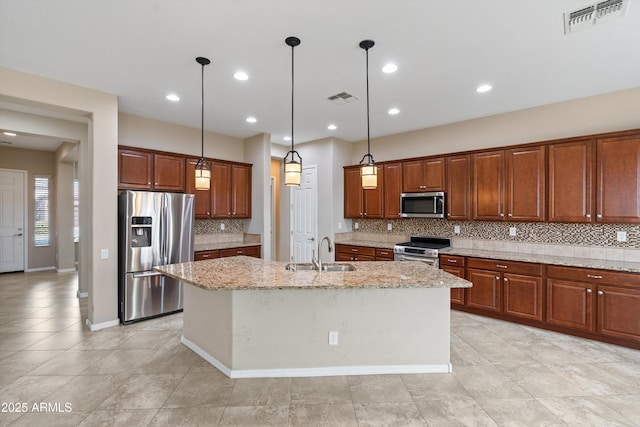 kitchen with stainless steel appliances, an island with sink, a sink, and visible vents