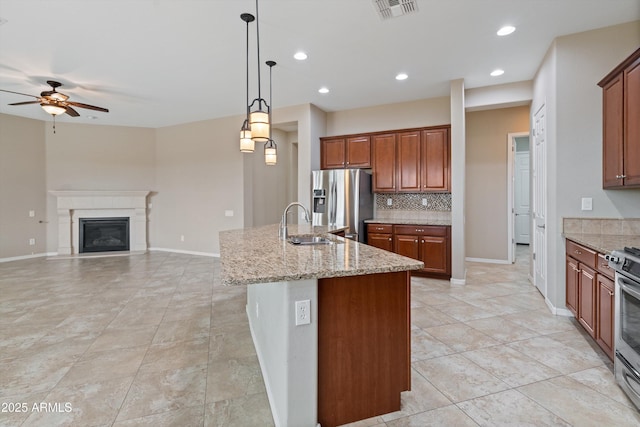 kitchen featuring tasteful backsplash, visible vents, appliances with stainless steel finishes, a sink, and light stone countertops