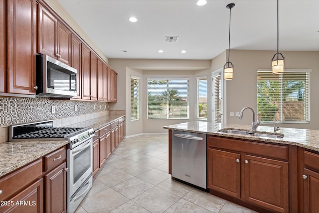 kitchen with stainless steel appliances, a sink, visible vents, hanging light fixtures, and tasteful backsplash