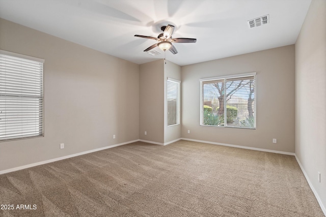 empty room with baseboards, carpet floors, visible vents, and a ceiling fan