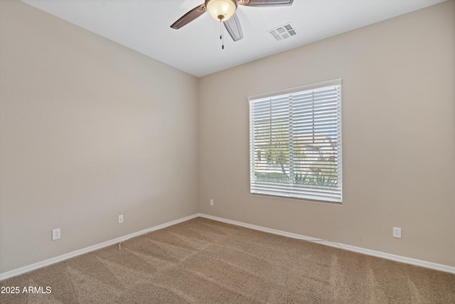 carpeted spare room featuring ceiling fan, visible vents, and baseboards