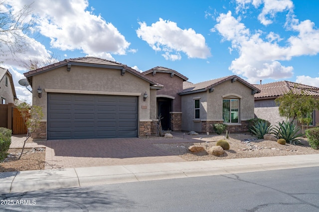 view of front of house with stone siding, decorative driveway, and stucco siding