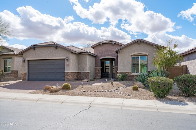 mediterranean / spanish-style home with a garage, stone siding, a tiled roof, driveway, and stucco siding