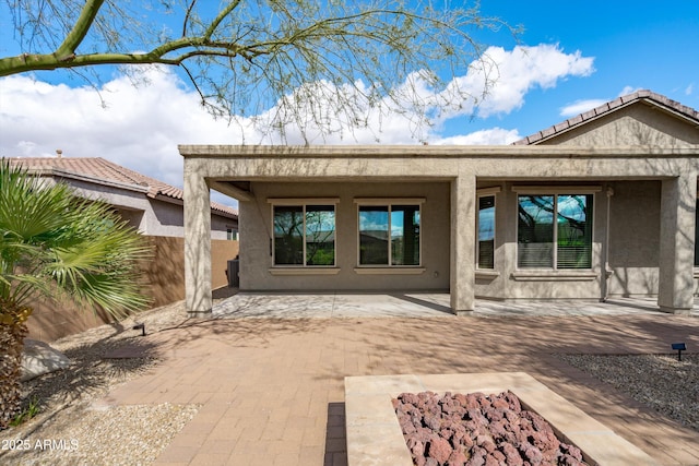 rear view of property with a tile roof, a patio, and stucco siding