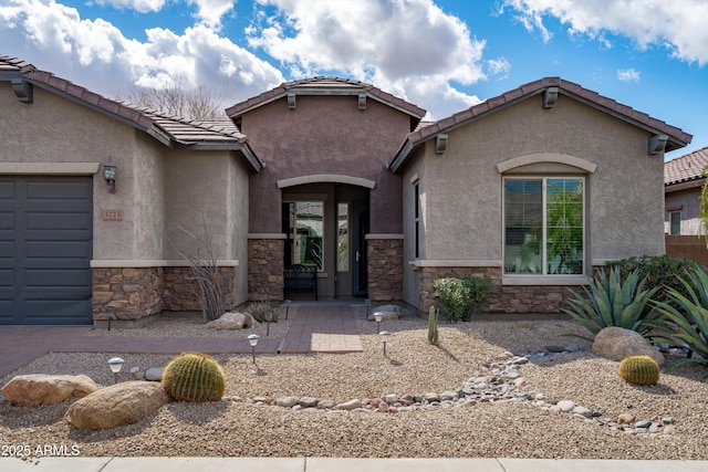 view of front facade featuring stone siding, a tile roof, an attached garage, and stucco siding