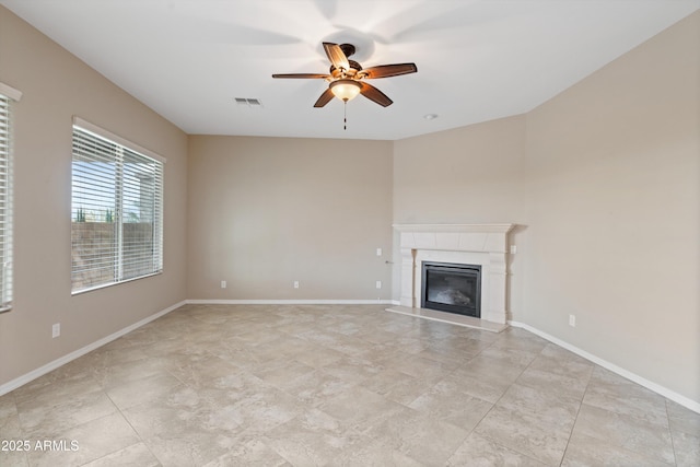 unfurnished living room featuring baseboards, visible vents, a ceiling fan, and a glass covered fireplace