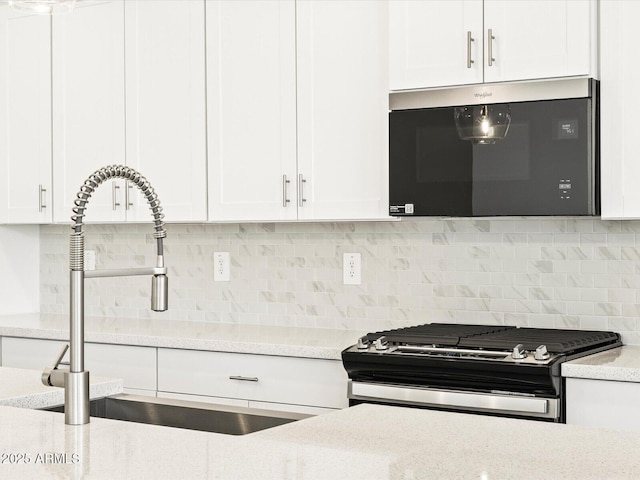 4032 S 176th Dr, Goodyear, AZ 85338 - kitchen featuring stainless steel microwave, range with gas stovetop, white cabinetry, and decorative backsplash