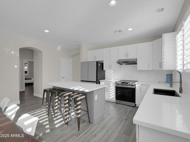 kitchen with visible vents, freestanding refrigerator, stainless steel range with electric cooktop, a sink, and under cabinet range hood