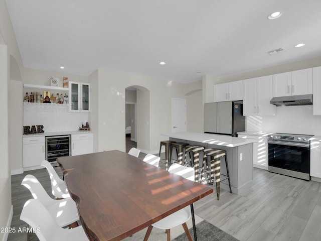 dining area with wine cooler, arched walkways, a dry bar, and recessed lighting