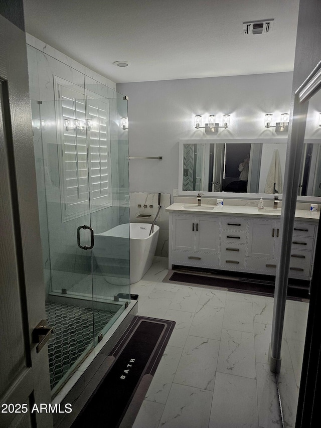 bathroom featuring marble finish floor, a soaking tub, visible vents, a stall shower, and a sink