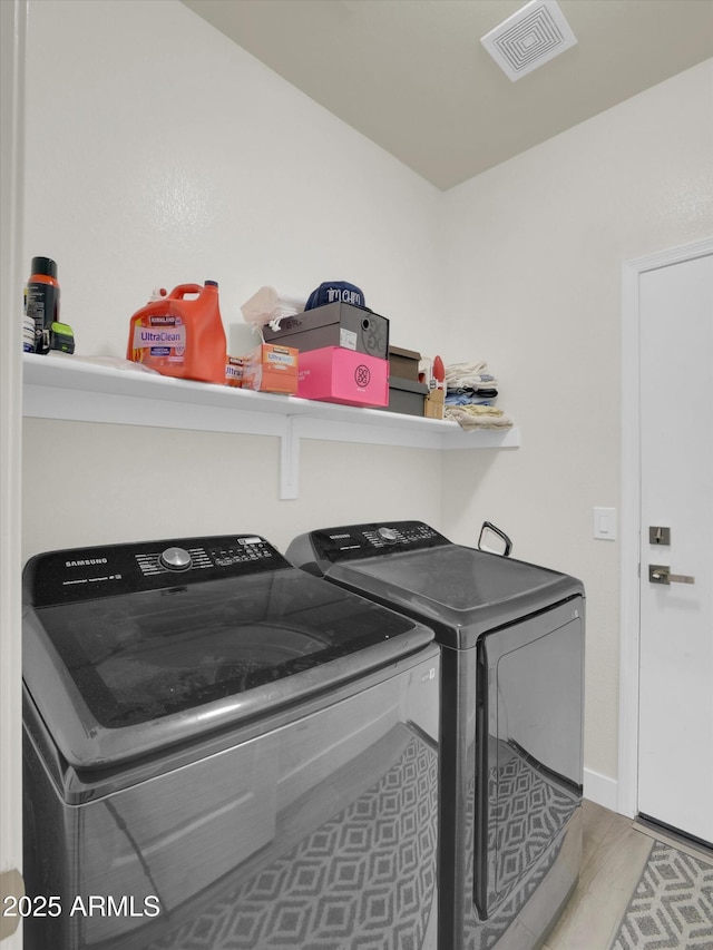 laundry room with laundry area, visible vents, baseboards, and separate washer and dryer