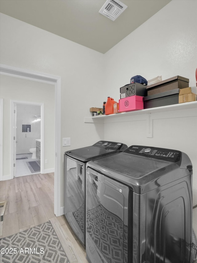 clothes washing area with visible vents, light wood-type flooring, laundry area, independent washer and dryer, and baseboards