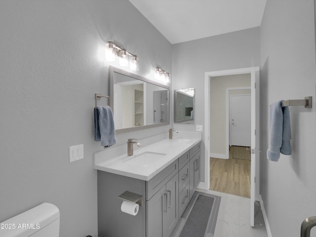 full bath featuring marble finish floor, a sink, toilet, and baseboards