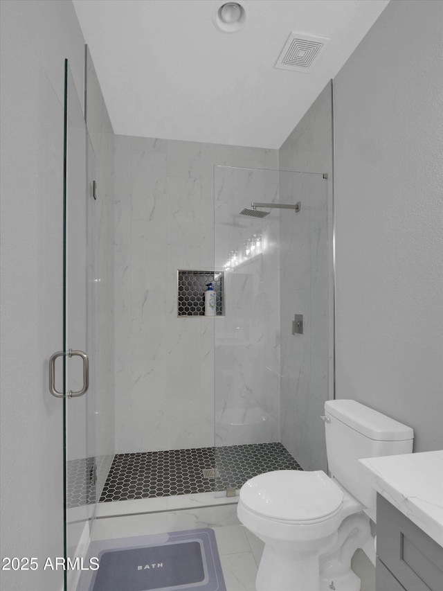 bathroom featuring a marble finish shower, visible vents, toilet, marble finish floor, and vanity