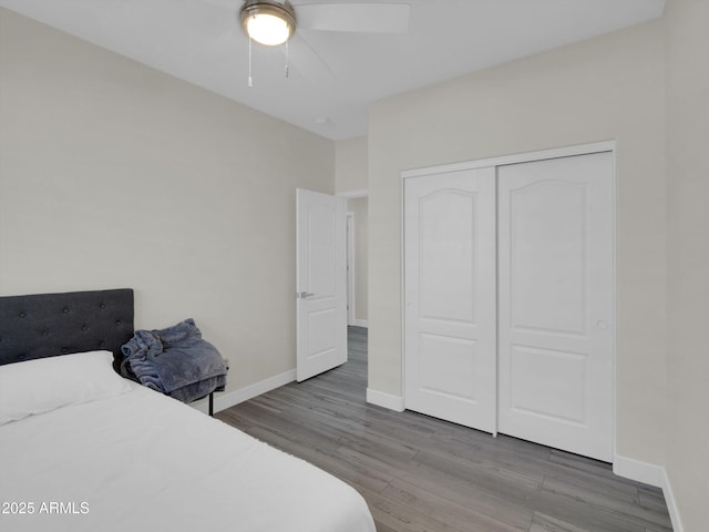 bedroom with a closet, ceiling fan, baseboards, and wood finished floors