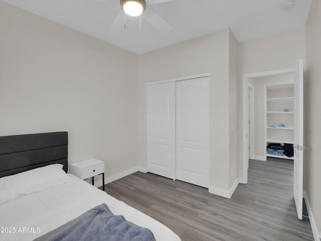 bedroom featuring ceiling fan, a closet, wood finished floors, and baseboards