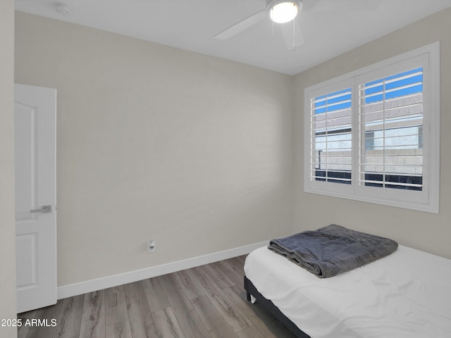 bedroom featuring wood finished floors, a ceiling fan, and baseboards