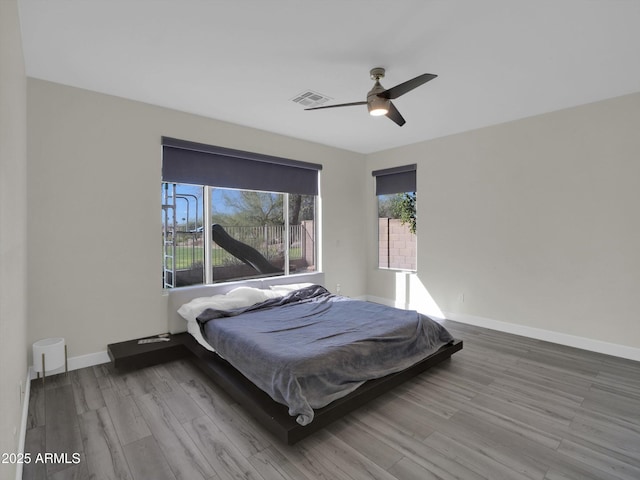 bedroom featuring a ceiling fan, baseboards, visible vents, and wood finished floors