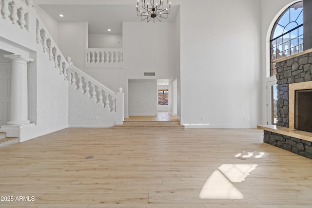 unfurnished living room featuring plenty of natural light, a stone fireplace, and light hardwood / wood-style flooring