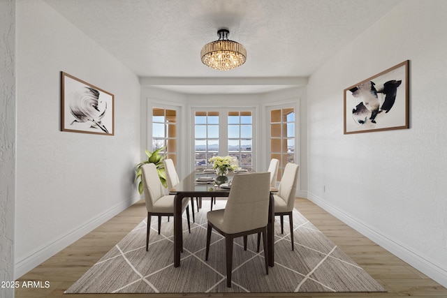 dining area featuring a textured ceiling, wood-type flooring, and a chandelier