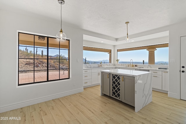 kitchen featuring white cabinetry, hanging light fixtures, light hardwood / wood-style flooring, and sink