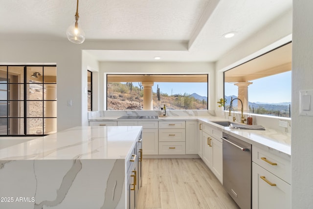 kitchen featuring decorative light fixtures, white cabinetry, stainless steel dishwasher, light stone counters, and a mountain view