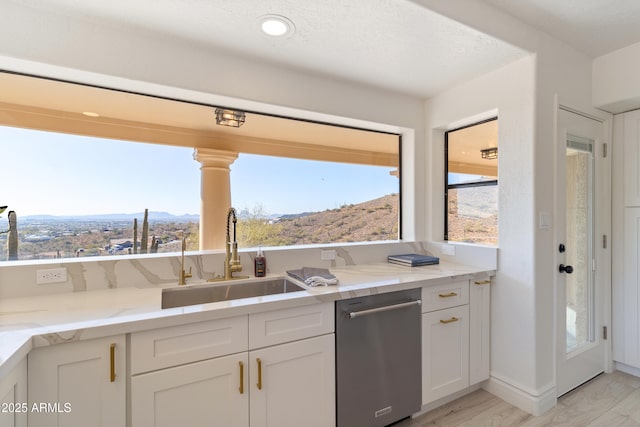 kitchen featuring sink, light hardwood / wood-style flooring, dishwasher, white cabinetry, and light stone counters