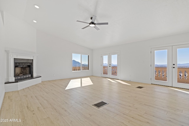 unfurnished living room with french doors, ceiling fan, vaulted ceiling, and light hardwood / wood-style floors