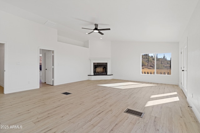 unfurnished living room featuring ceiling fan, lofted ceiling, a fireplace, and light hardwood / wood-style flooring