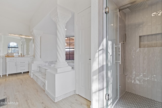 bathroom with hardwood / wood-style flooring, tiled shower, vanity, and ornate columns