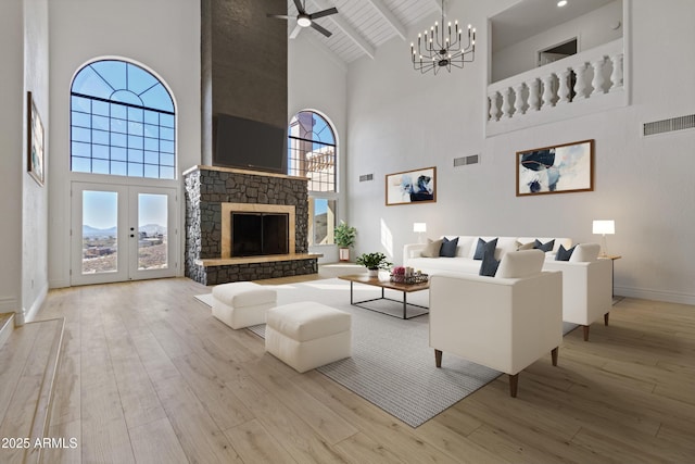 living room featuring beamed ceiling, a fireplace, high vaulted ceiling, and light wood-type flooring