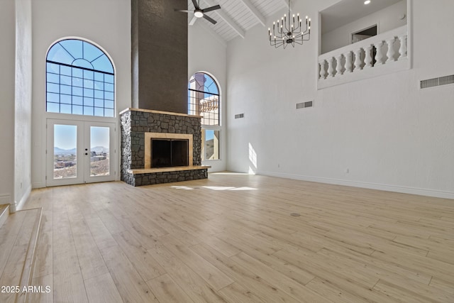 unfurnished living room with light hardwood / wood-style flooring, high vaulted ceiling, a fireplace, ceiling fan with notable chandelier, and beamed ceiling