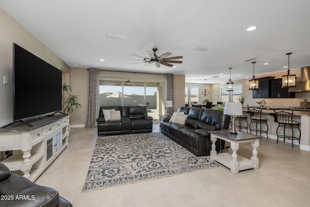 living room featuring ceiling fan with notable chandelier and light tile patterned flooring