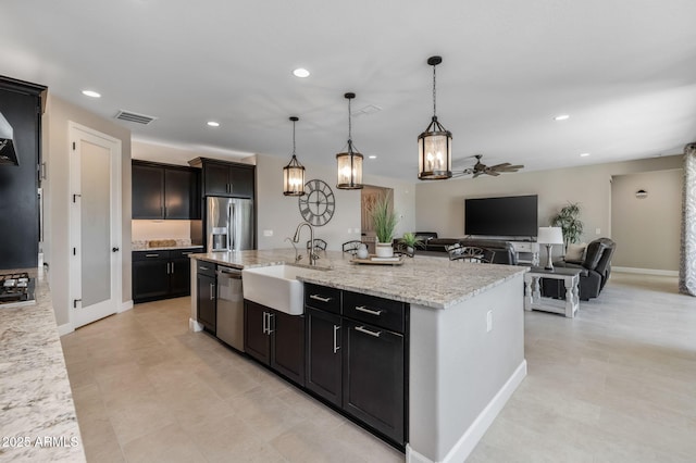 kitchen featuring decorative light fixtures, stainless steel appliances, a kitchen island with sink, ceiling fan, and sink