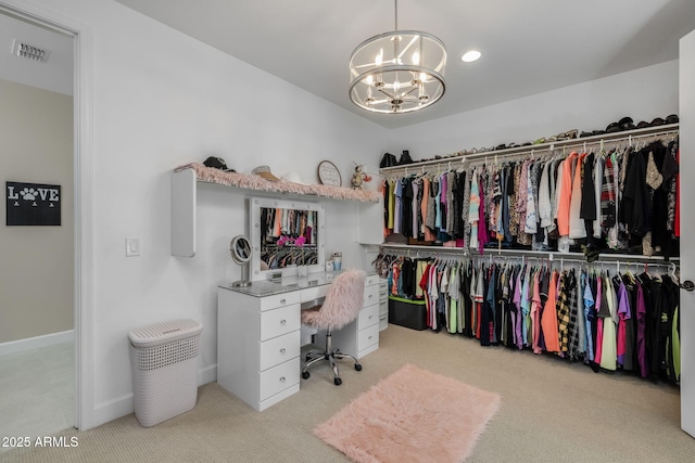 spacious closet with light colored carpet and a notable chandelier